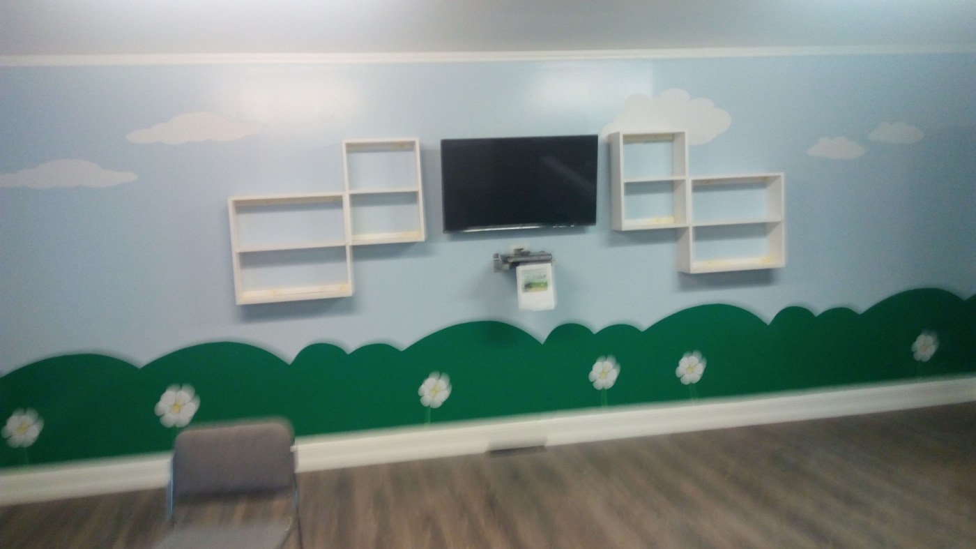 Children's room with a hand-painted sky and meadow mural