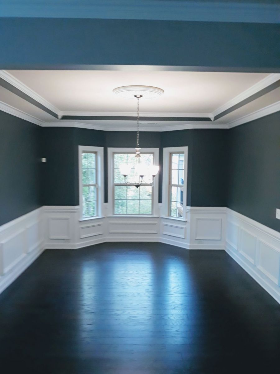 Formal dining room painted deep slate blue with white wainscoting