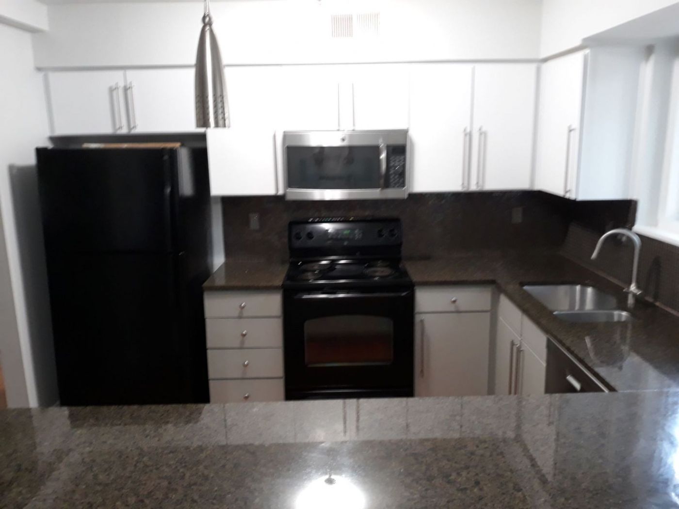 Galley kitchen cabinets repainted crisp white above dark counters